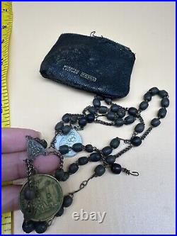 An antique religious Medal attached to the rosary Bead