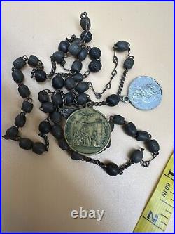 An antique religious Medal attached to the rosary Bead